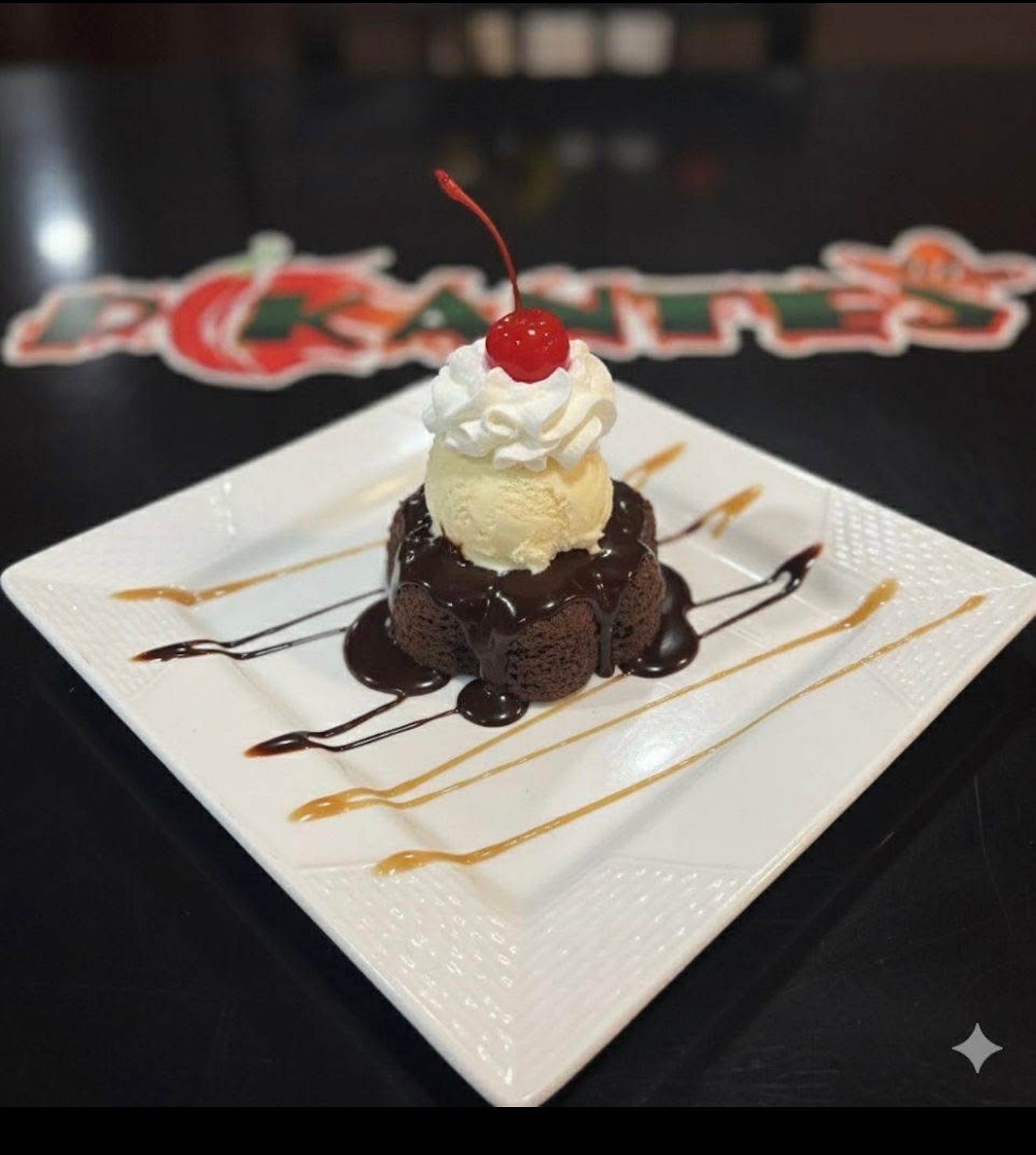 Warm chocolate brownie topped with vanilla ice cream, whipped cream and a cherry with caramel drizzle