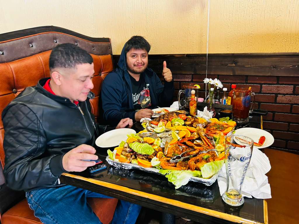Guests sharing a table-size mariscada seafood platter with avocado, citrus and micheladas