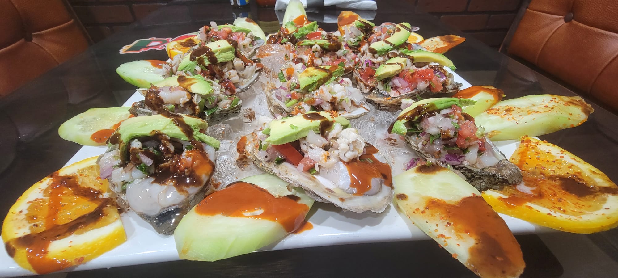 Platter of ostiones al estilo Pikante's on the half shell topped with shrimp, pico de gallo, avocado and chamoy