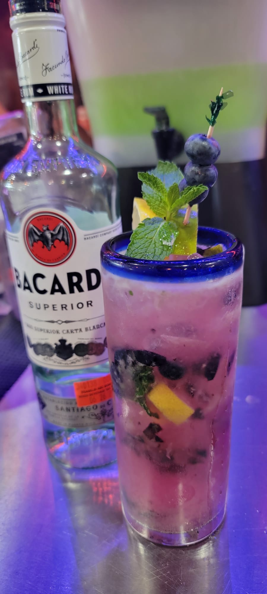 Blueberry mojito with fresh mint, lemon and blueberry skewer in a tall glass
