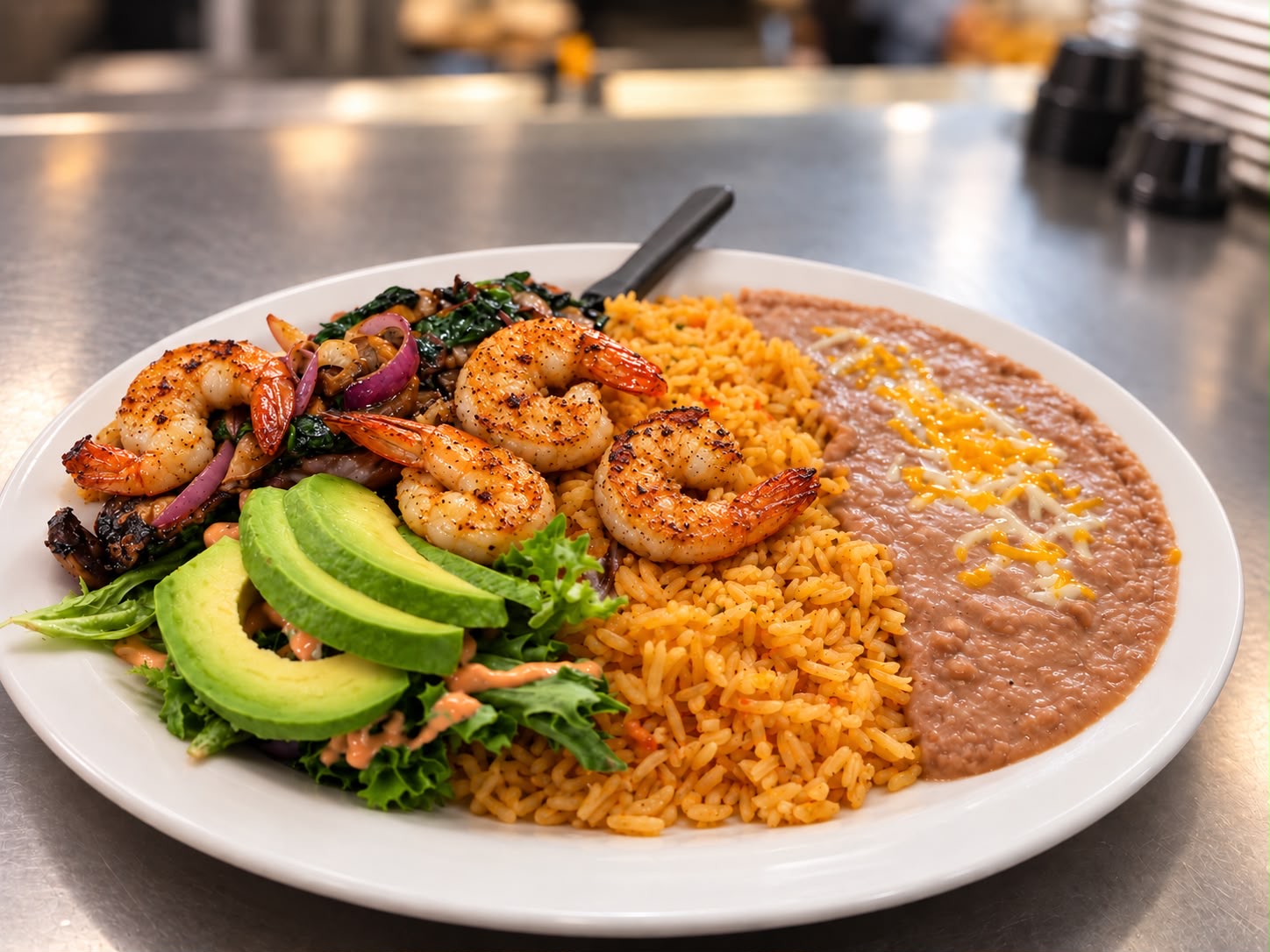 Grilled shrimp plate with Mexican rice, refried beans, sliced avocado and greens